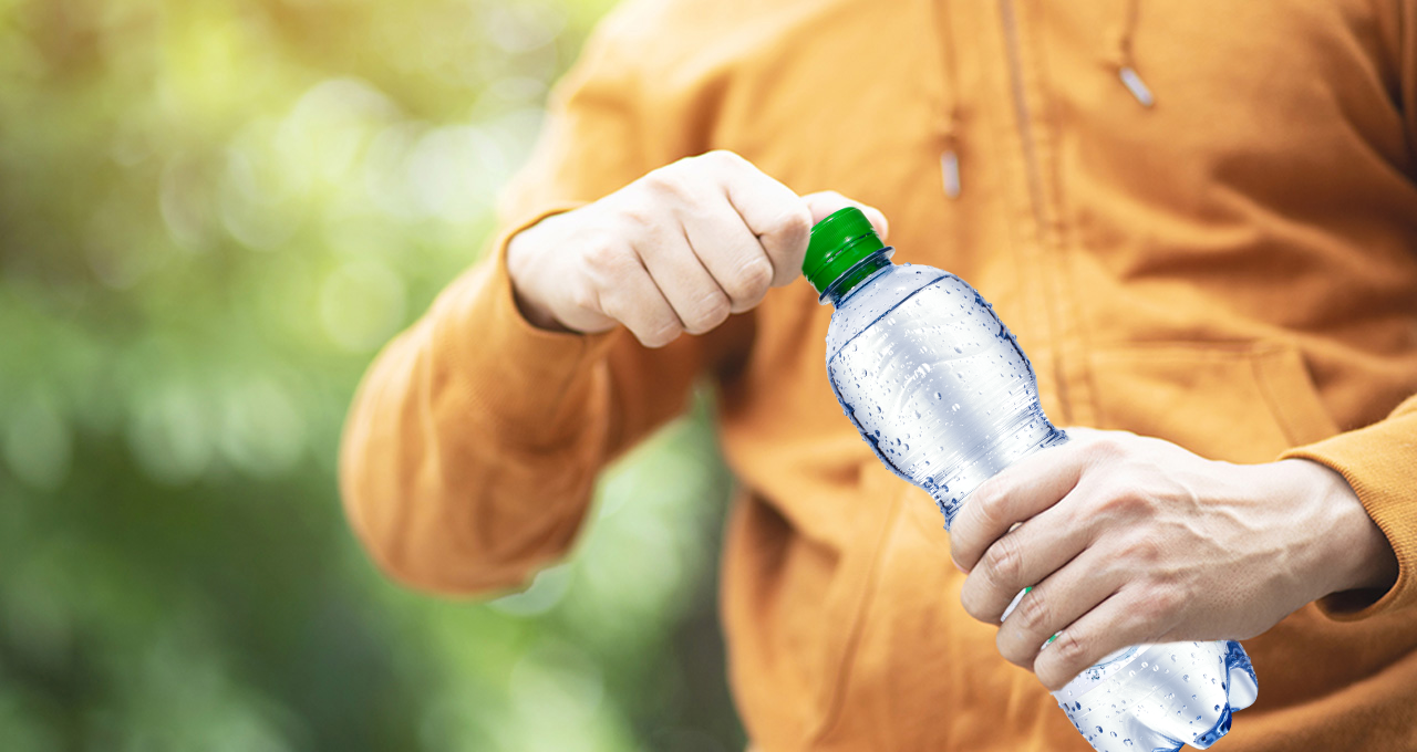 Person dreht Mineralwasser medium Flasche auf