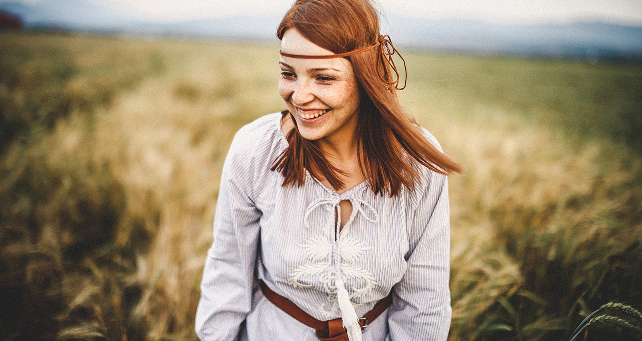 Lachende Frau mit Haarband vor einem Feld