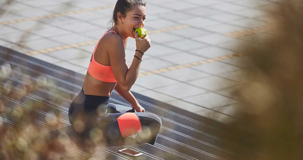 Sportliche Frau beißt in Apfel